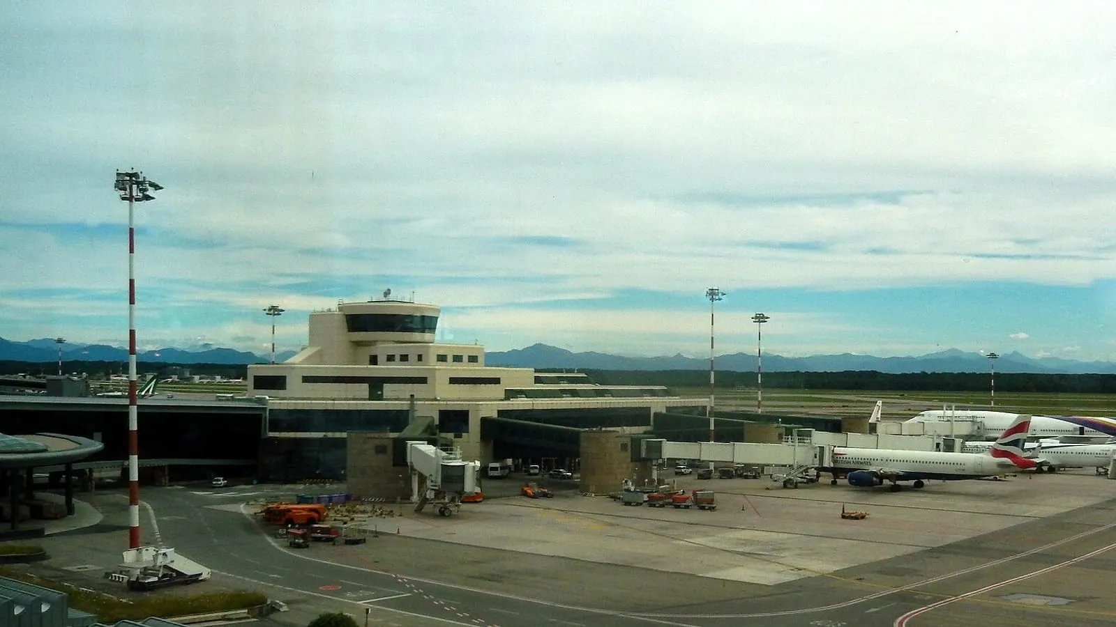 Terminal 1 apron at Milan Malpensa Airport, with the Alps on the horizon