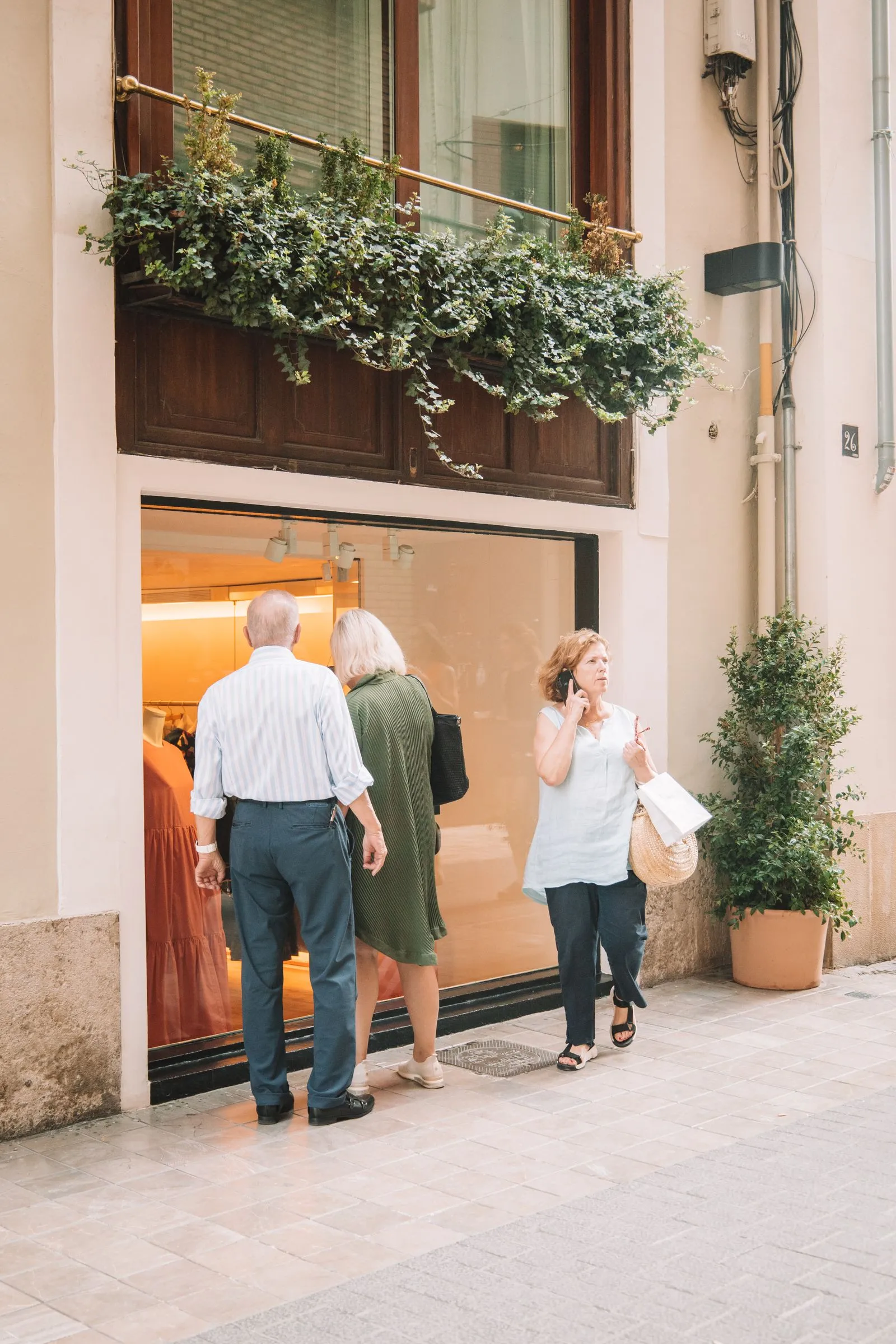 Shoppers browsing an elegant boutique storefront window on a European shopping street